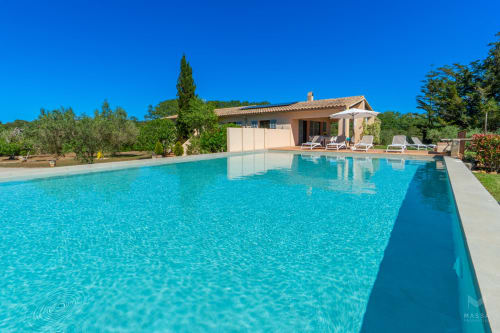 Villa de lujo en Artà con piscina de agua turquesa, tumbonas y casa de estilo mediterráneo rodeada de vegetación
