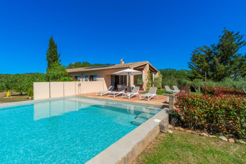 Villa de lujo en Artà con piscina turquesa, tumbonas y jardín mediterráneo en día soleado