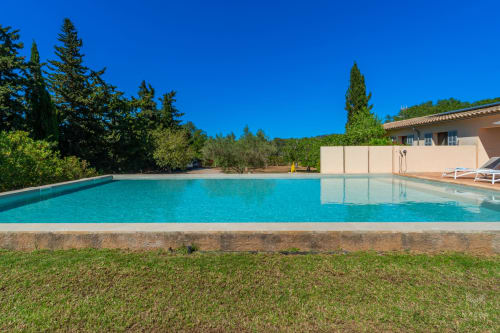 Piscina color turquesa con jardín impecable, villa moderna y cipreses en Massa Properties, Artà, España