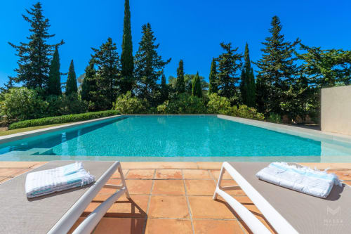Piscina de lujo en Massa Properties de Artà con tumbonas, agua turquesa y cipreses mediterráneos
