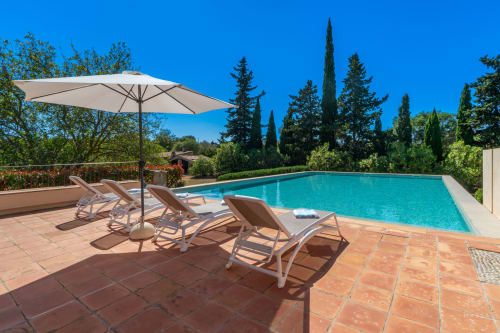 Terraza de lujo con piscina en Massa Properties en Artà: tumbonas, sombrilla y agua turquesa