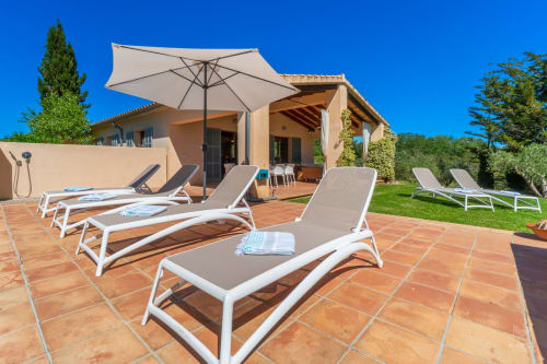 Terraza soleada con tumbonas y sombrilla en villa Massa Properties en Artà, España