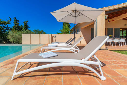 Lujosa zona de descanso junto a la piscina en Massa Properties, Artà, con tumbonas, sombrilla y villa mediterránea