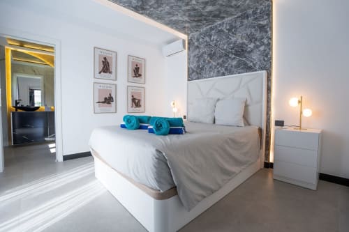 Habitación moderna en Villa La Menta, Gran Canaria con cama blanca, cabecero de mármol, almohadas azules y decoración contemporánea