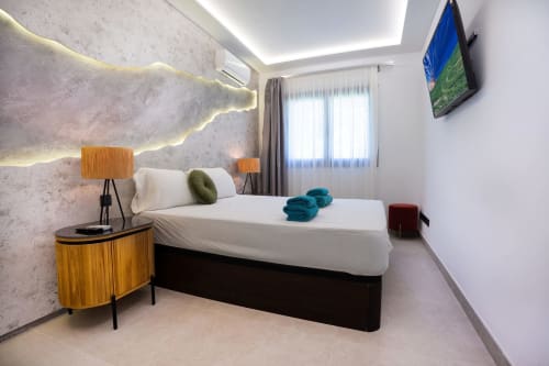 Dormitorio moderno en Villa La Menta, Gran Canaria, con ropa de cama blanca, mesitas de noche de madera e iluminación ambiental