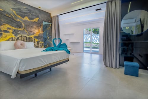 Dormitorio moderno en Villa La Menta Gran Canaria con vistas a la piscina, cama blanca, detalles turquesas y obra de arte abstracta