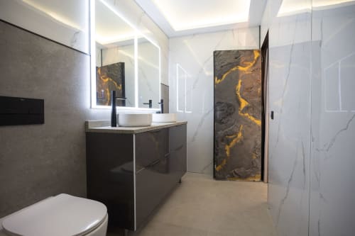 Baño moderno de Villa La Menta, Gran Canaria con baldosas de mármol, mueble negro, espejo iluminado y decoración elegante