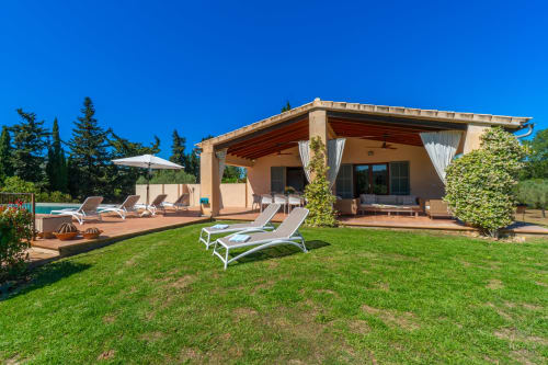 Villa de lujo en Artà con terraza, tumbonas y jardín cuidado bajo cielo azul