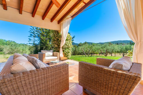 Terraza de lujo en Massa Properties, Artà, con asientos de mimbre, olivares y vistas a las montañas