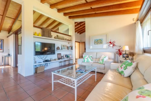 Luminoso salón en Massa Properties de Artà con vigas de madera vista, sofás color crema, mueble TV y suelo de baldosa terracota