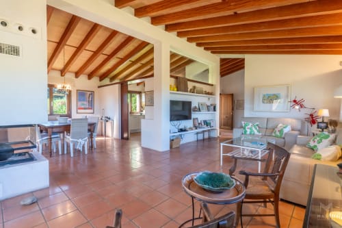 Amplio salón diáfano en Artà con vigas de madera vista, baldosas de barro, mobiliario moderno y luz natural