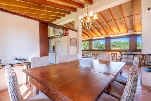 Amplio comedor con vigas de madera, araña de luces y vistas a la terraza en Massa Properties, Artà