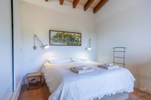 Dormitorio luminoso en Massa Properties de Artà con ropa de cama blanca, vigas de madera y decoración rústica