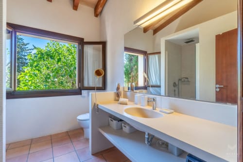 Baño moderno en Massa Properties, Artà, con doble lavabo, vistas al jardín e iluminación natural desde vigas de madera