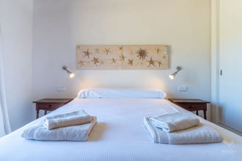 Dormitorio moderno en Massa Properties de Artà con cabecero de arte estrellado, ropa de cama blanca e iluminación ambiental