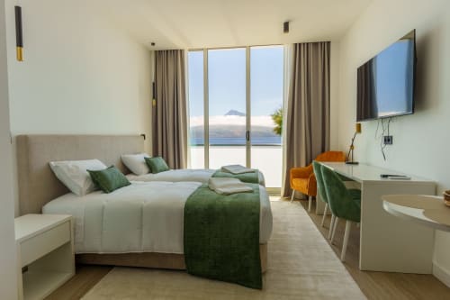 Quarto moderno com vista para o mar em Suites Avenue Lux, Horta. Cama, TV de ecrã plano, secretária e varanda com vista