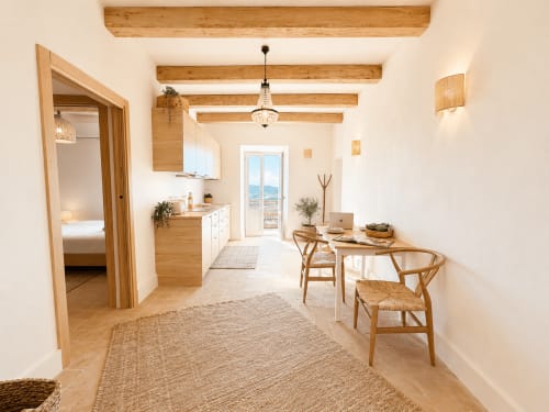 Bright Tuscan apartment suite with wooden beams, dining table, kitchen, and sea view balcony in Montemassi