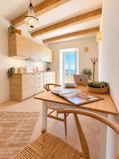 Bright kitchen workspace in Tuscan townhouse with wooden beams, sea view balcony, and work desk with plants