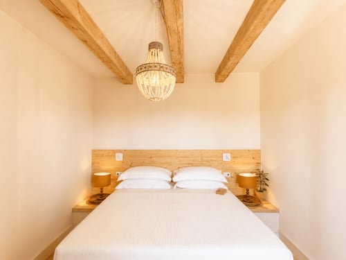 Elegant bedroom at Tuscan Townhouse with exposed wooden beams, crystal chandelier, and wooden headboard with white pillows