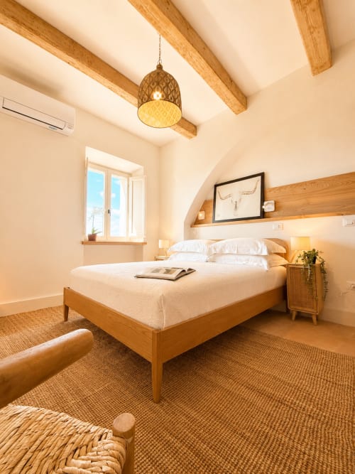 Tuscan Townhouse bedroom with wooden beams, white walls, natural light, and garden views in Montemassi