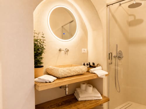 Modern bathroom in Tuscan Townhouse with stone sink, illuminated mirror, rainfall shower, and garden view