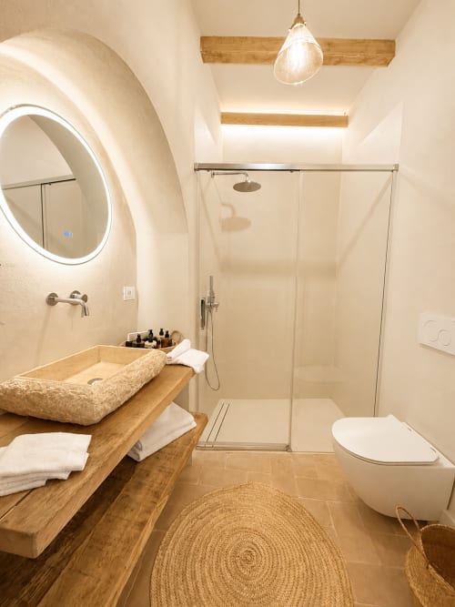 Modern bathroom in Tuscan Townhouse apartment with stone sink, rainfall shower, heated mirror, and wooden accents in