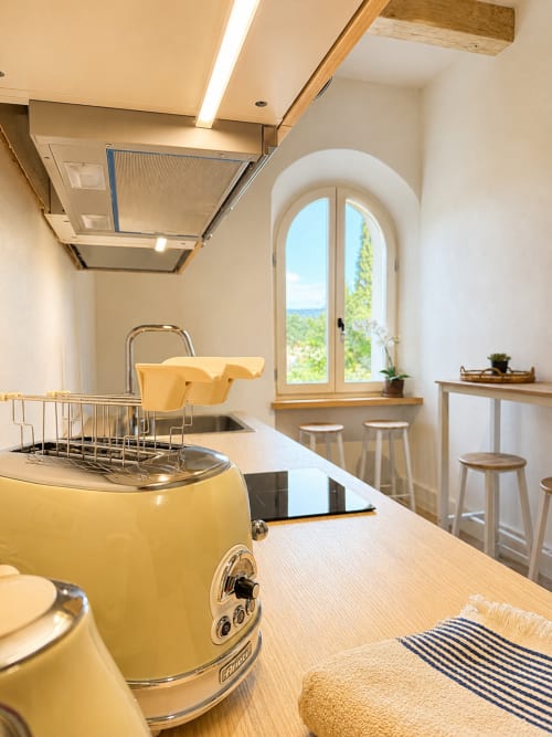 Modern kitchen in Tuscan Townhouse with yellow vintage appliances, arched window overlooking garden, wooden counters
