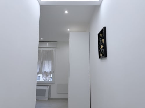 Corridoio moderno della Dream Suite Bologna con pareti bianche, illuminazione incassata e opera d'arte contemporanea nera