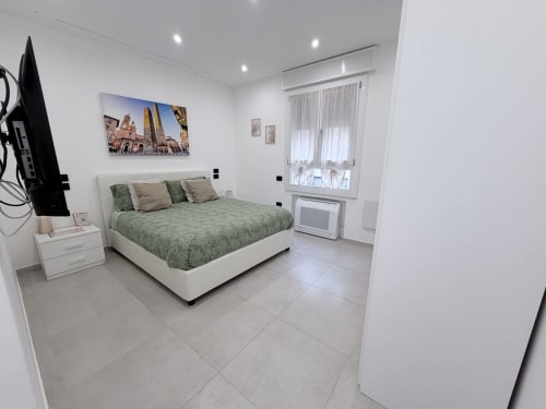 Camera doppia Sabò presso Dream Suite Bologna con biancheria verde, arredamenti bianchi, comfort moderni e vista sulla corte interna