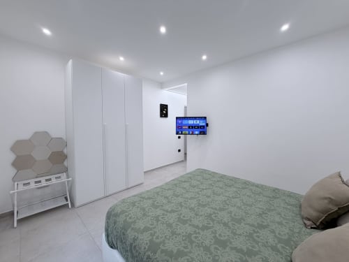 Camera doppia Sabò presso Dream Suite Bologna con letto matrimoniale, armadio bianco, TV a parete e design minimalista moderno