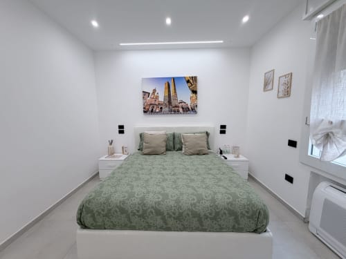 Camera moderna della Dream Suite Bologna con biancheria verde a motivi, opere d'arte e illuminazione contemporanea