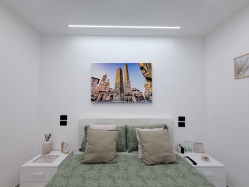 Camera doppia Sabò presso Dream Suite Bologna con biancheria verde, cuscini beige e opere raffiguranti le torri di Bologna sopra il letto