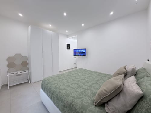 Camera moderna presso Dream Suite Bologna con letto verde, armadio bianco, TV a parete e arredamento minimalista