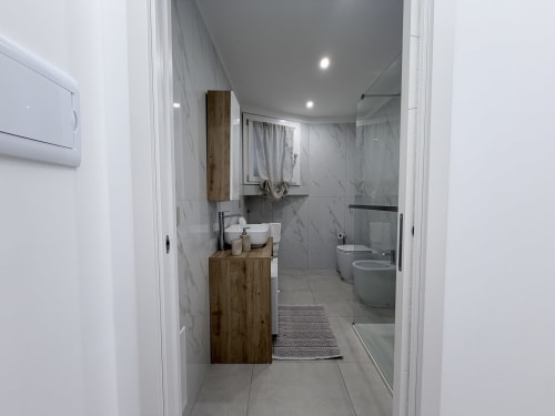 Bagno moderno della Dream Suite Bologna con piastrelle in marmo, mobile in legno, WC, bidet e doccia con box