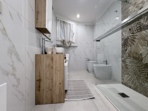 Moderno bagno nella suite Sabò del Dream Suite Bologna con pareti in marmo, mobile in legno, doccia, WC e bidet