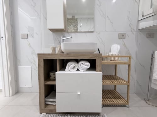 Bagno moderno della Dream Suite Bologna con piastrelle in marmo, mobile in legno, lavabo a coppa e asciugamani arrotolati in deposito