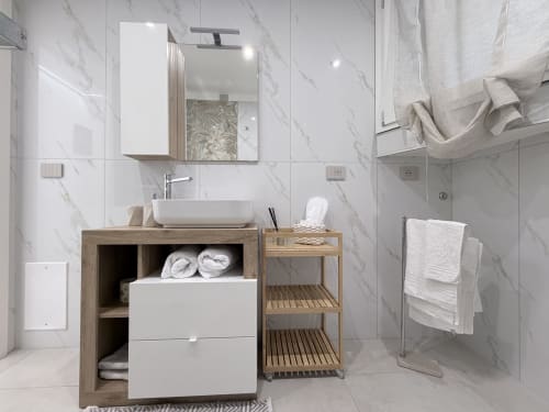 Bagno in marmo moderno nella Dream Suite Bologna con vanità in legno, lavabo bianco a bacinella, mobile con specchio e doccia walk-in