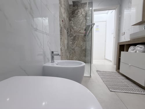 Bagno moderno nella Dream Suite Bologna con vasca bianca, lavabo freestanding, doccia in vetro, piastrelle di marmo e