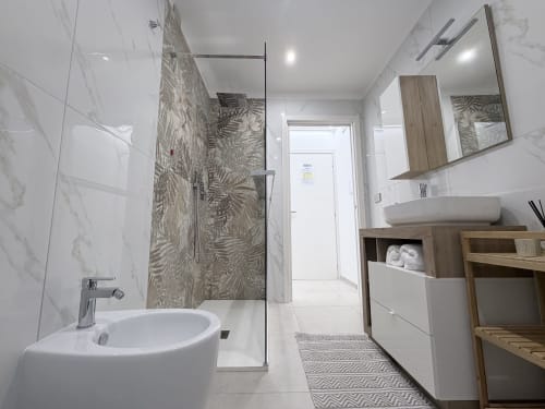 Bagno moderno della Dream Suite Bologna con piastrelle in marmo, doccia walk-in, lavabo a bacinella, vanity in legno e illuminazione dello specchio