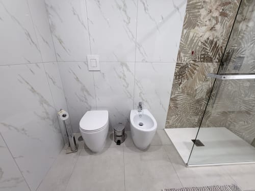 Bagno moderno nella Sabò Double Room di Dream Suite Bologna con piastrelle in marmo bianco, toilette, bidet e doccia con accesso diretto
