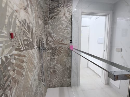 Bagno moderno nella suite Sabò del Dream Suite Bologna con piastrelle decorative, doccia con box in vetro e pavimento in marmo