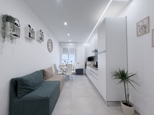 Moderna camera doppia Sabò presso Dream Suite Bologna con divano grigio, cucina bianca, zona pranzo e vista sulla corte interna