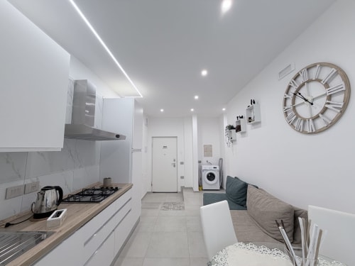 Moderna cucina e zona living nella Suite Doppia Sabò di Dream Suite Bologna con mobili bianchi, piano cottura, lavatrice e