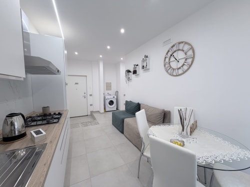 Moderno monolocale open-plan Dream Suite Bologna con angolo cottura, divano letto, tavolo da pranzo e lavatrice