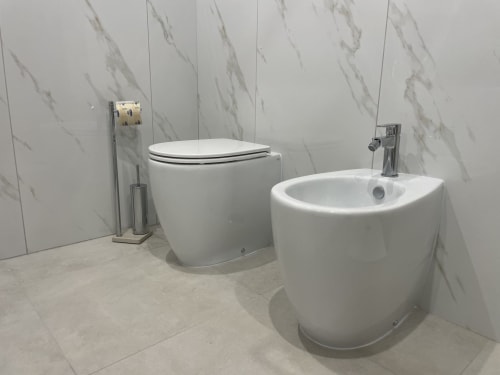 Bagno moderno nella camera Sabò di Dream Suite Bologna con bidet e wc bianchi curvi, pareti effetto marmo e cromature
