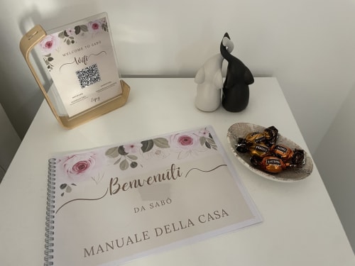 Amenità di benvenuto nella camera Sabò di Dream Suite Bologna: candela profumata, guida turistica, elementi decorativi neri e cioccolatini