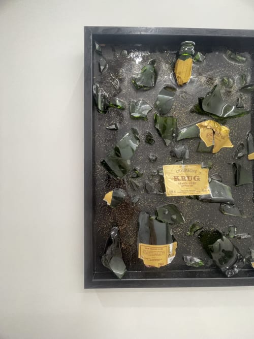 Bottiglie di champagne rotte e frammenti di vetro sparsi su superficie scura, esposizione della Dream Suite Bologna