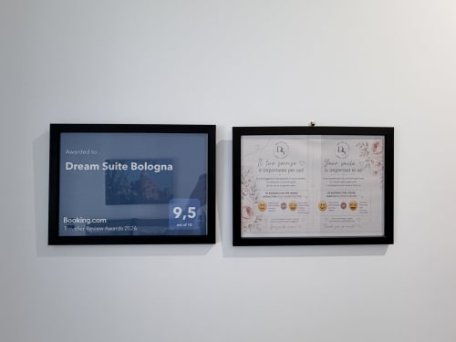 Due certificati incorniciati per Dream Suite Bologna: valutazione Booking.com 9.5 e attestati di recensioni ospiti su parete bianca