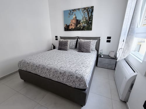 Camera moderna della Dream Suite Bologna con letto matrimoniale, testata grigia, biancheria a motivi e condizionatore d'aria