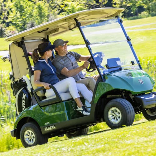 Deux clients en voiturette de golf Yamaha verte sur un parcours ensoleillé à STAYnGOLF, Cagnes-sur-Mer